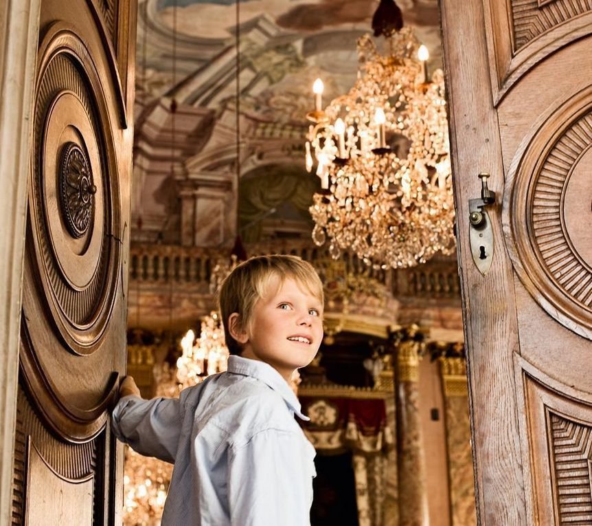 A young boy opens a door at Ludwigsburg Residential Palace